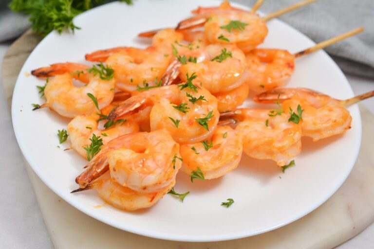 Air fryer bang bang shrimp on a skewer on a white plate.