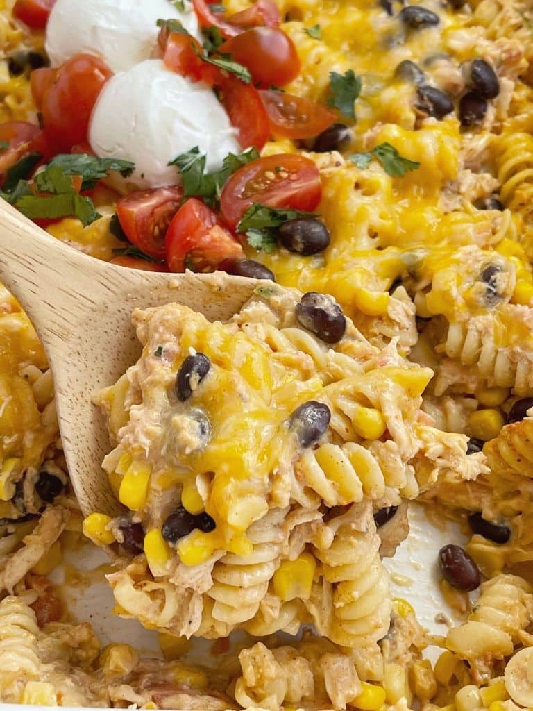 Fiesta chicken casserole being served out of a casserole dish with a wooden spoon