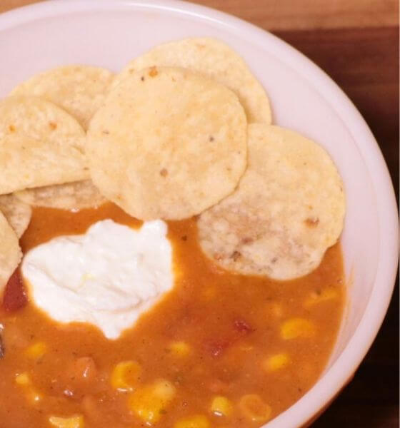 crockpot taco soup with sour cream and tortilla chips on top in a white bowl