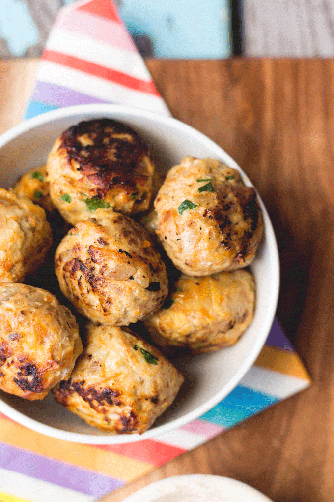 chicken meatballs in a white bowl on a wood background with colorful striped napkin
