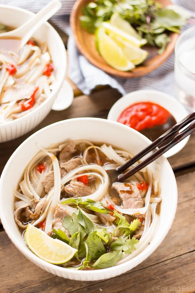 Slow Cooker Beef Pho served in a white bowl next to chopsticks