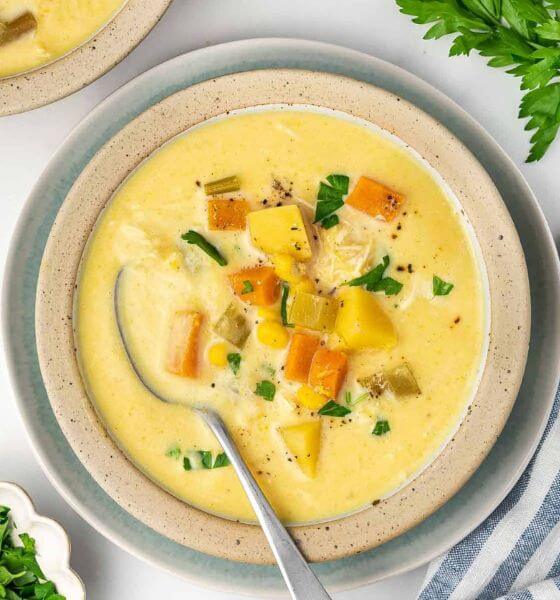 slow cooker chicken and corn soup in white and blue bowl with a spoon in the bowl