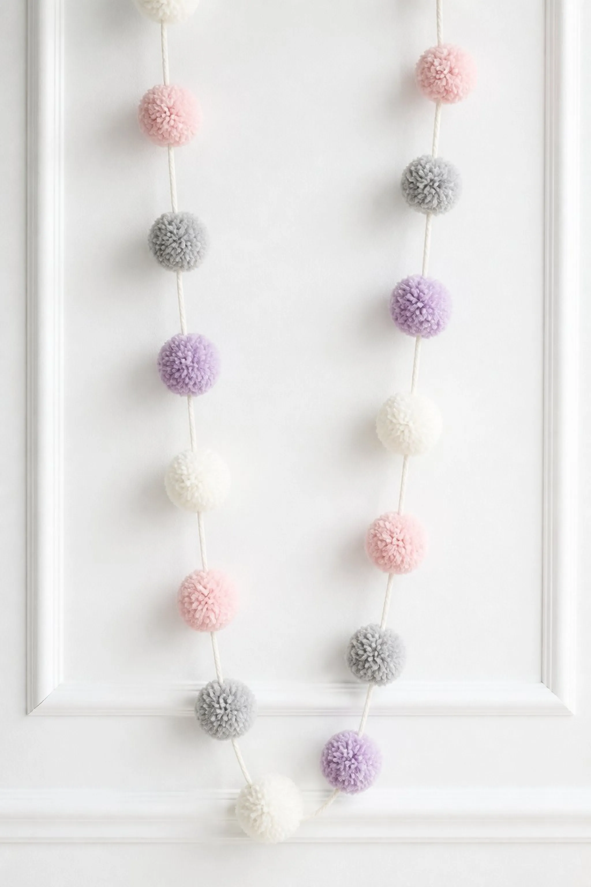 Whimsical pom-poms linked for dynamic garland